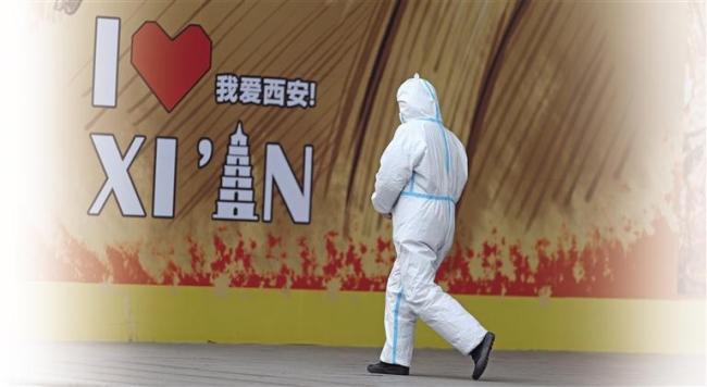 1月5日，在西安市长安北路，一名志愿者从商场门前走过。赵晨/摄