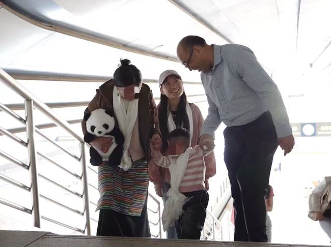 小卓玛在妈妈和当代医护人员的陪同下抵达北京，协会副会长唐召明前去迎接
