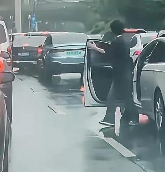 一男子下車后氣呼呼地扔掉了前車放置的三角錐